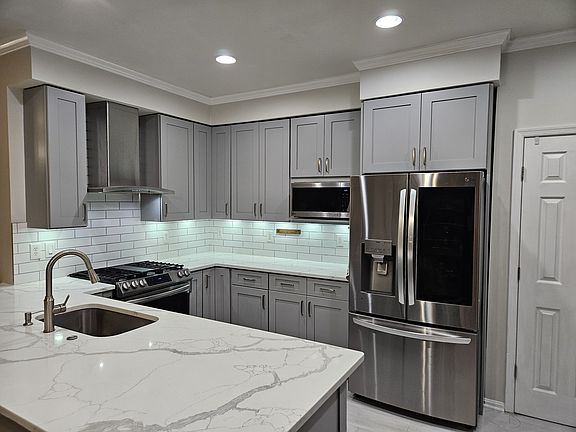 Kitchen with oversized sink and top-of-the-line stainless steel appliances, including French door refrigerator and GE Profile vent hood that vents to the outside.