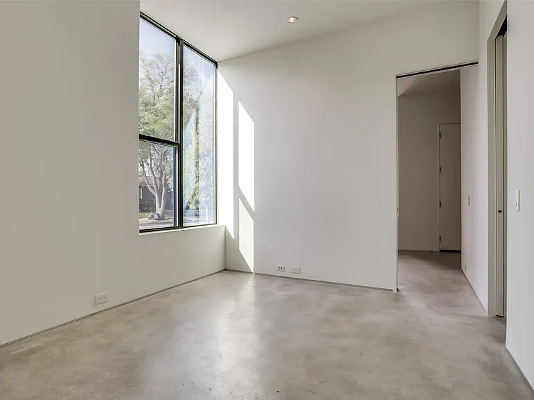Room featuring a large, multi-pane window with black framing, polished concrete flooring, recessed ceiling lighting, and a neutral wall palette