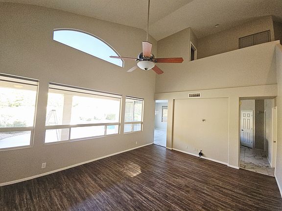 High ceiling living room with panoramic backyard views and modern shades