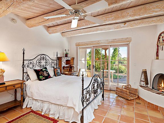 Primary bedroom with a king bed, kiva fire place, a ceiling fan, and sliding doors to the private patio