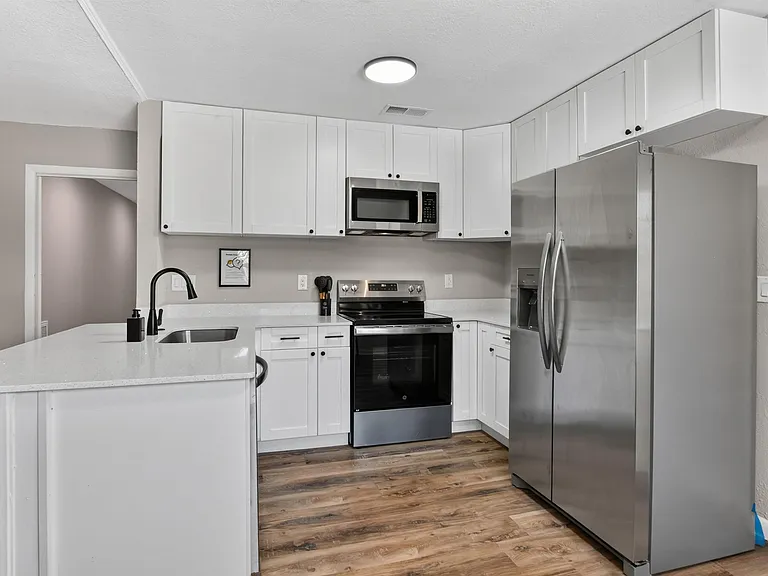 U-shaped kitchen with ample cabinet storage, generous counters, and stainless steel appliances including fridge and microwave