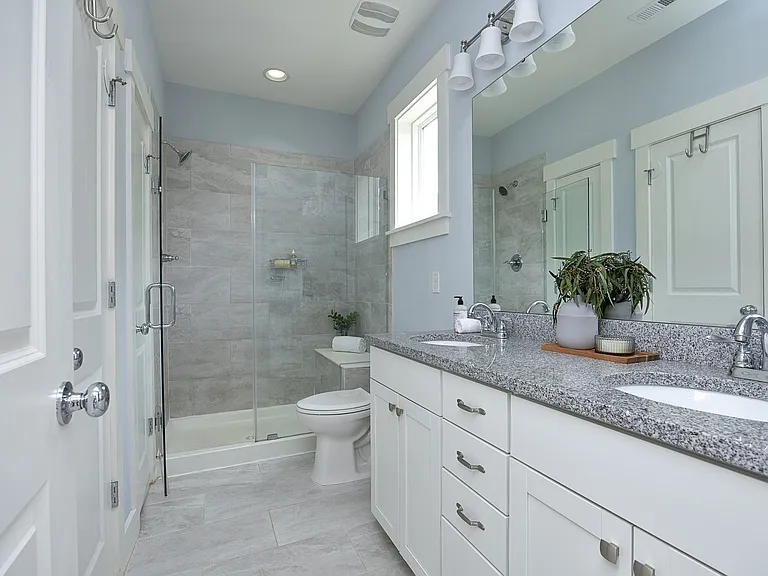 Primary bathroom with granite countertops, double sink, frameless shower