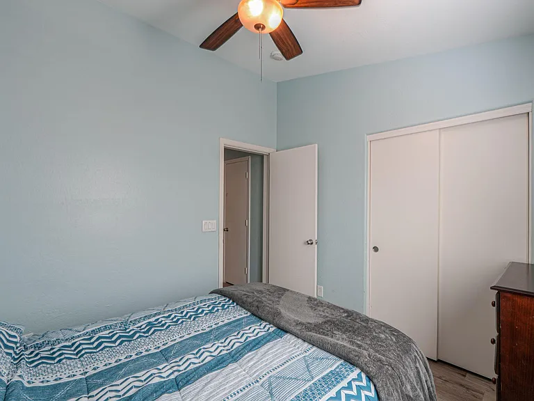 Bedroom with ceiling fan, sliding-door closet, and space for a full/queen bed plus a dresser.
