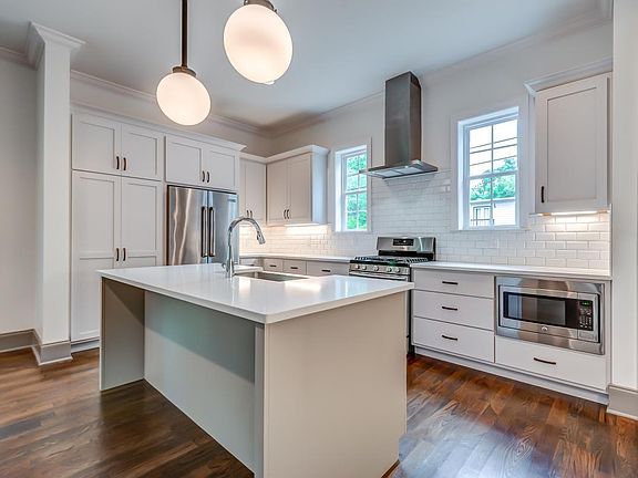 Large island with room for 3 barstools. Counter-depth Jenn-Air refrigerator; Five-burner gas range