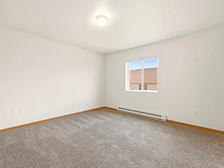 Step into a bright, spacious bedroom at Paramount at the Bluffs Apartments, featuring plush carpeting and ample natural light. This is the perfect space to unwind and make your own. Schedule a tour today to envision your new life here!