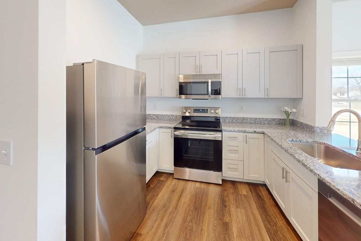 The Jane kitchen opens to the living room, and features granite countertops and stainless steel appliances, including a microwave and dishwasher.