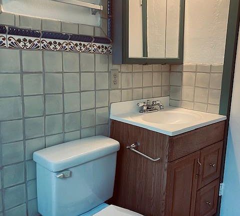 full bathroom with sink and mirrors, toilet, tub, Mexican tiles, and plain tile flooring