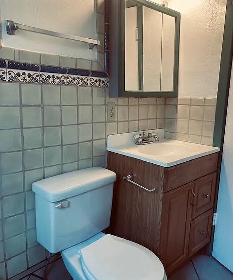 full bathroom with sink and mirrors, toilet, tub, Mexican tiles, and plain tile flooring