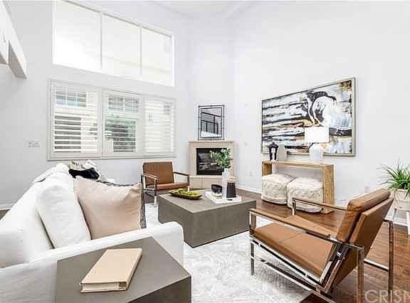 Bright main living area with hardwood floors, gas fireplace, plantation shudders