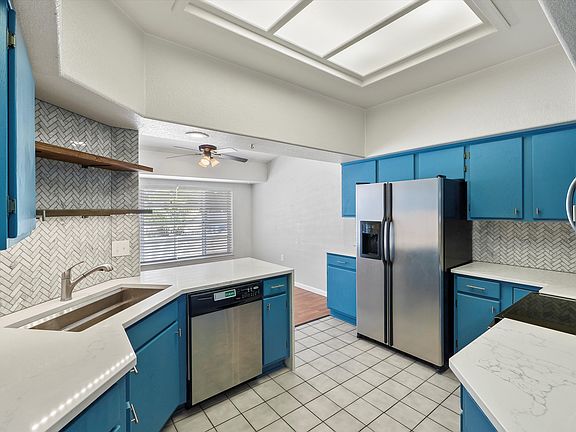 Stainless steel side by side refrigerator with dishwasher and open shelving above the sink