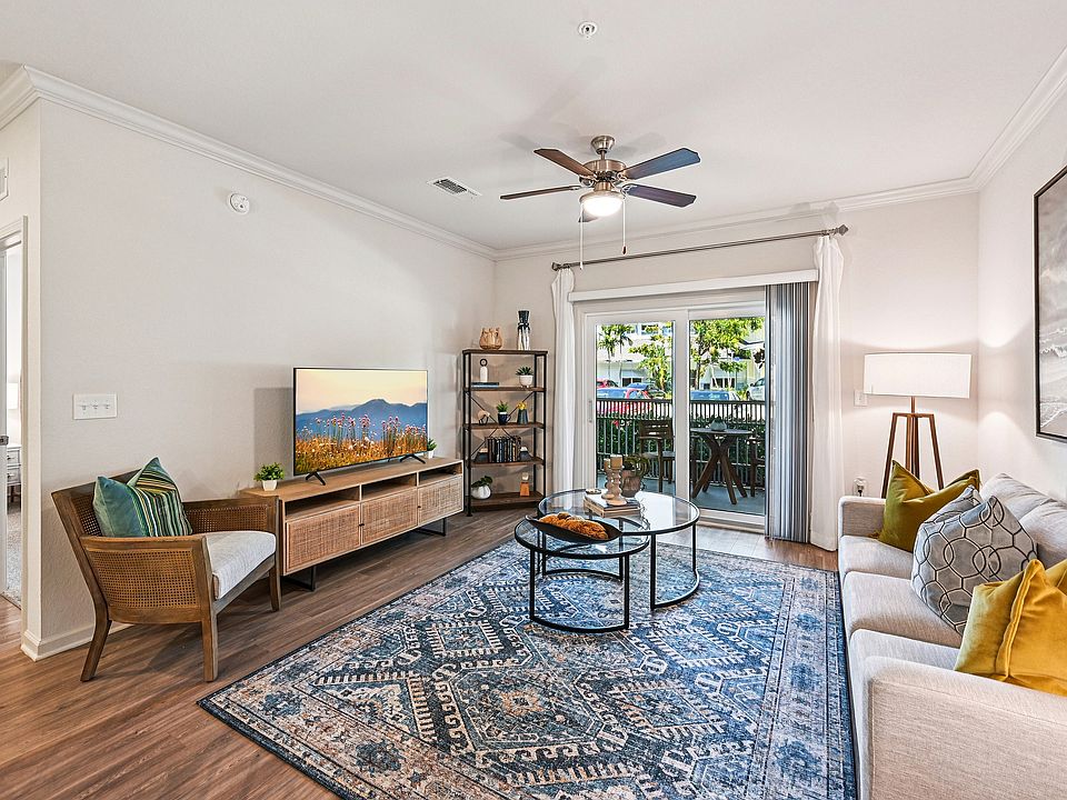 Bright and inviting living room with elegant decor, featuring a spacious sitting area, cozy couch, and stylish accent pieces. Large glass doors open to a serene outdoor patio, perfect for relaxation.