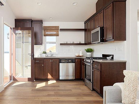 Stainless Kitchen with modern appliances: Microwave, 4-burner gas stove and oven, dishwasher, and refrigerator.