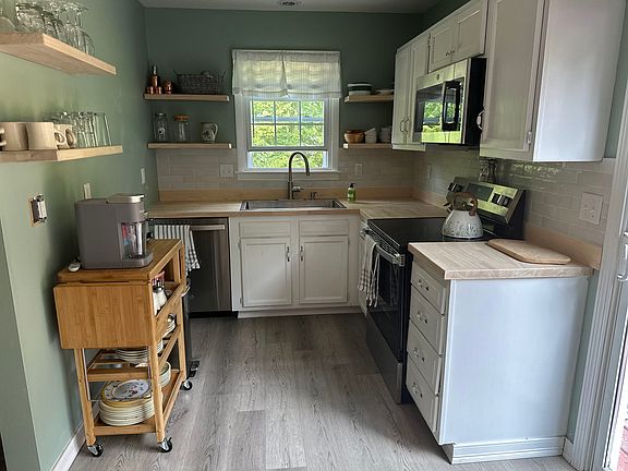 Open concept floating shelves with dishes for 8, new sink, new dishwasher. Pots and pans, new butcher block counter tops
