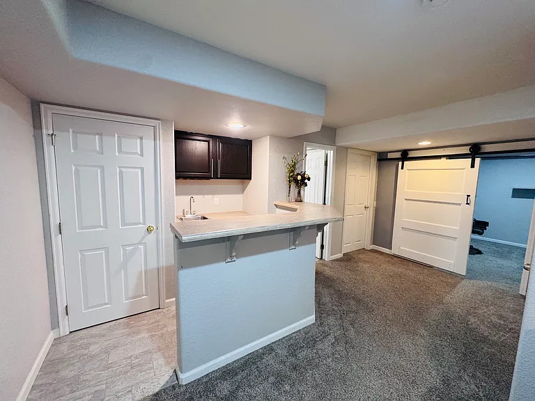 Breakfast kitchenette with a small sink, mini refrigerator, cabinet storage, and breakfast bar seating.