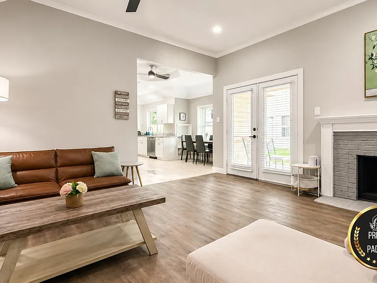 Open living area with seating, fireplace, and French doors, flowing into the kitchen and dining space for easy living.