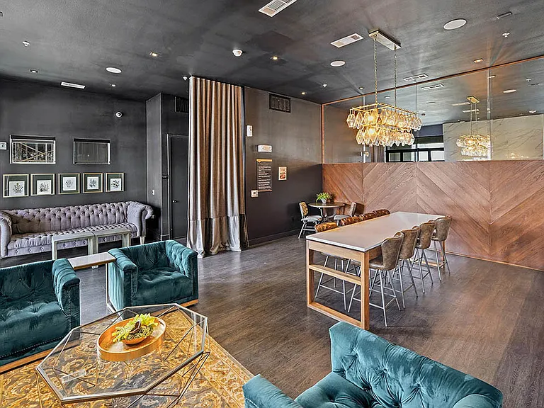 Resident lounge with plush seating, wood style floor, and large TVs.