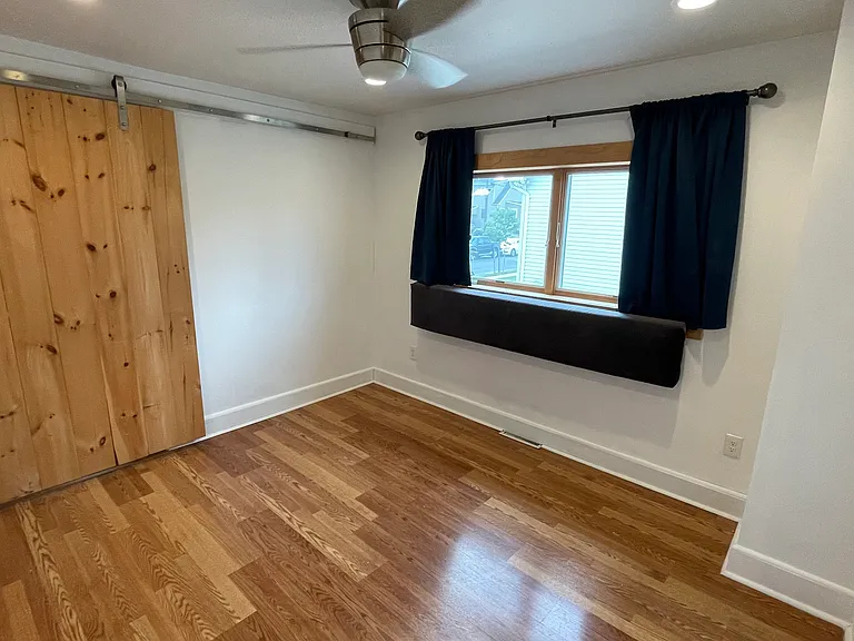 Primary bedroom with hardwood floors, ceiling fan, natural light, and convenient private bath access.