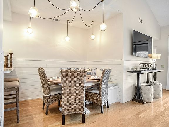 Gather around in this inviting dining space with custom lighting, a built-in bench, and woven chairs that add a touch of coastal elegance. The perfect spot for family meals or entertaining guests.