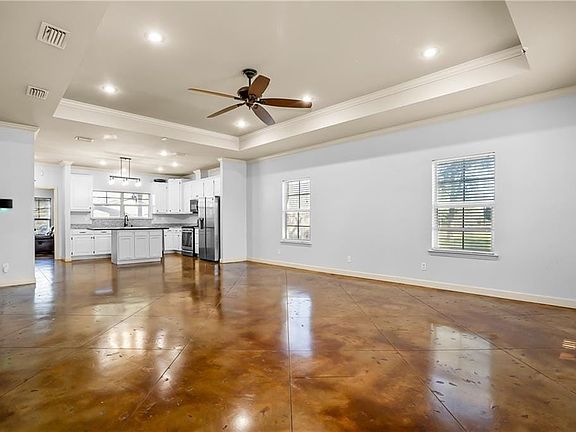 Unfurnished living room with ornamental molding, a tray ceiling, visible vents, and baseboards
