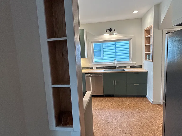 View from dining room into the kitchen with cork floors. Living room and dining room have restored oak flooring.