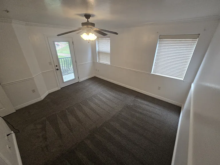 The spacious master bedroom, with private patio access, brand new carpet, and fresh paint. The master bedroom also has sound insulation installed in the ceiling. Not pictured: the private master bathroom with walk-in closet access.
