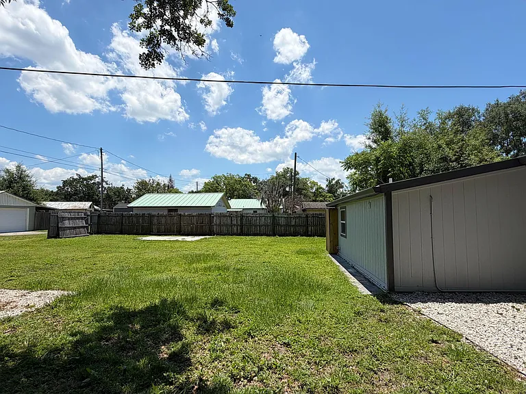 Spacious fenced backyard with a level grassy lawn and open sky views, offering room for outdoor activities and relaxing.