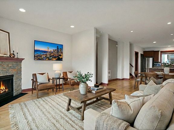 Bright, open living space featuring hardwood floors and a cozy gas fireplace, with an easy flow to the dining area and kitchen_ideal for comfortable daily living and hosting guests.