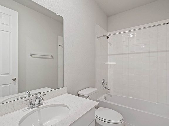 The secondary bath features tile flooring, white cabinetry and light countertops and a shower tub co