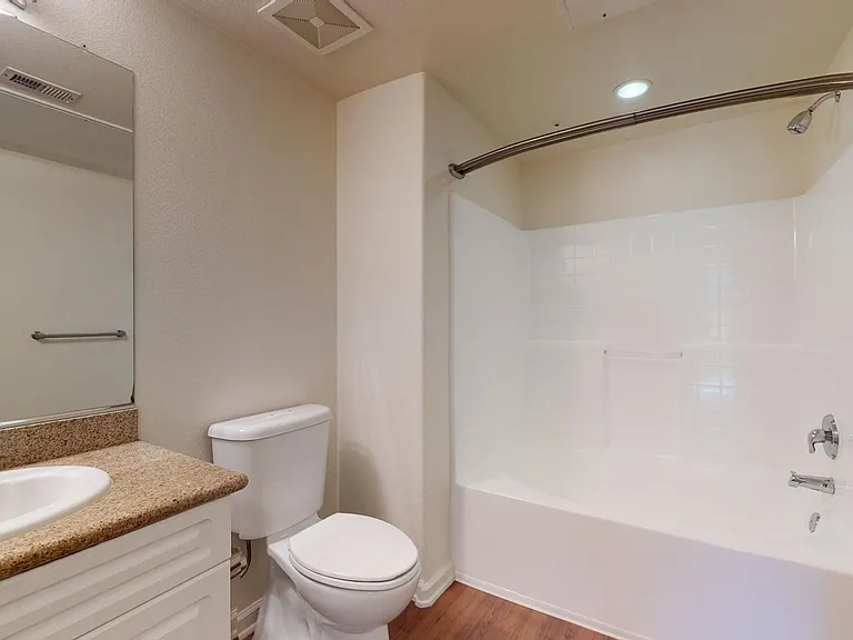 Apartment bathroom with wood-style flooring.