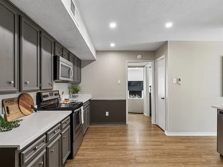 Kitchen has a walk-in pantry and opens to the powder bath, wet bar and living room beyond.