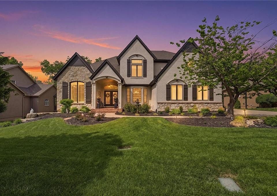 Stately residence featuring a stone and stucco exterior, dark gable roofing, and decorative window shutters