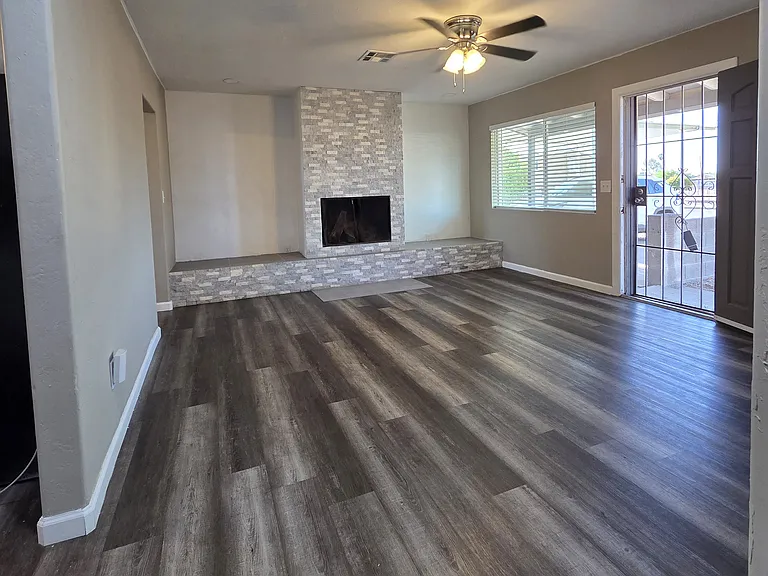 Living room includes a working fire place, front security door, and ceiling fan