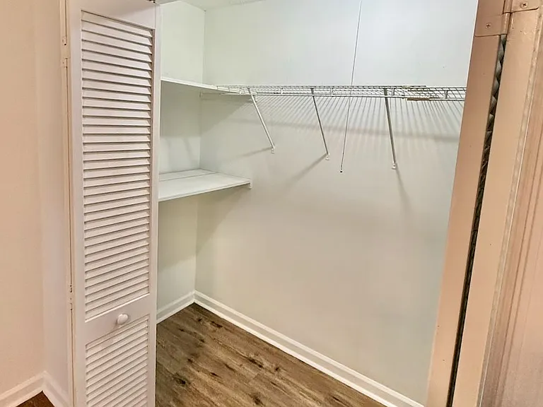 Organized primary closet_ - walk-in layout with built-in shelf keeps clothes and accessories neatly arranged - vinyl plank floors and bright overhead light make getting ready effortless every day.