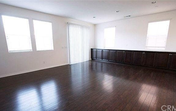 This photo shows the downstairs living room, with newly installed cabinets for extra storage space, as well as hardwood floors, 