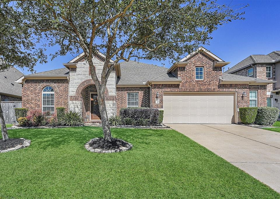 Welcome Home! A brick and stone elevation is surrounded by lush landscape and mature trees offering great curb appeal.