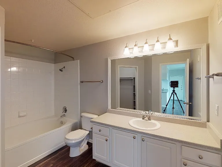 Apartment bathroom with large soaking tub and wood-style flooring.