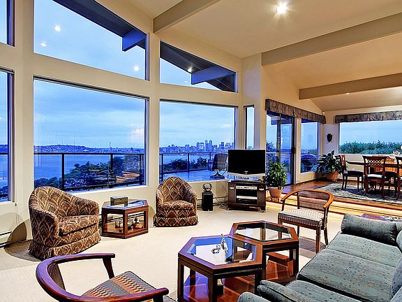 The living room with walls of windows and vaulted ceilings is open to the dining room making enterta