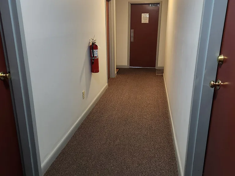 Hallway leading to laundry room located next door to unit and storage cubicle across the way 4 ft x 4ft x 8 ft