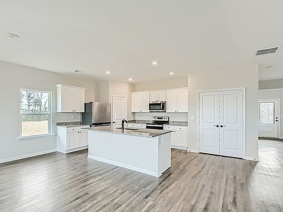 Designer kitchen with white cabinetry, granite countertops, and recessed lighting.