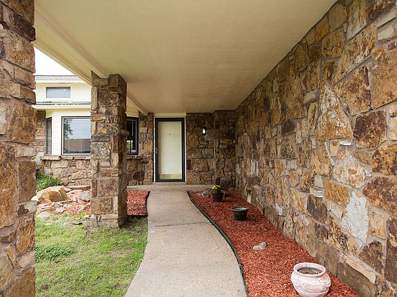 Covered front porch with lovely landscape beds.