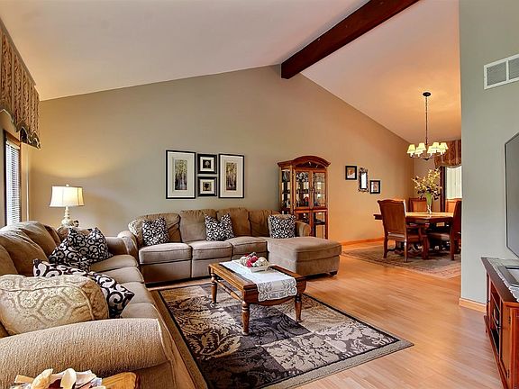 Spacious living room with vaulted ceiling and wood beam accent.