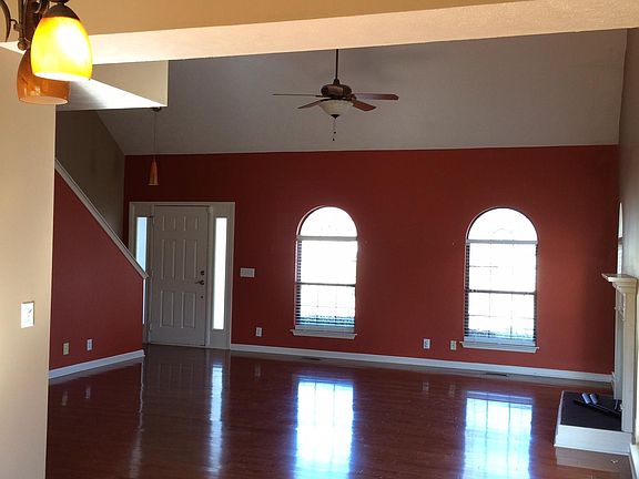 A view from the dining room, looking into the living room and at the front door. Stairs in front of the door lead upstairs to two bedrooms, Jack n Jill bathroom and bonus room