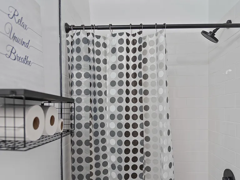 Tiled shower with rainfall-style showerhead, curved rod, and convenient wall shelving for toiletries and linens.