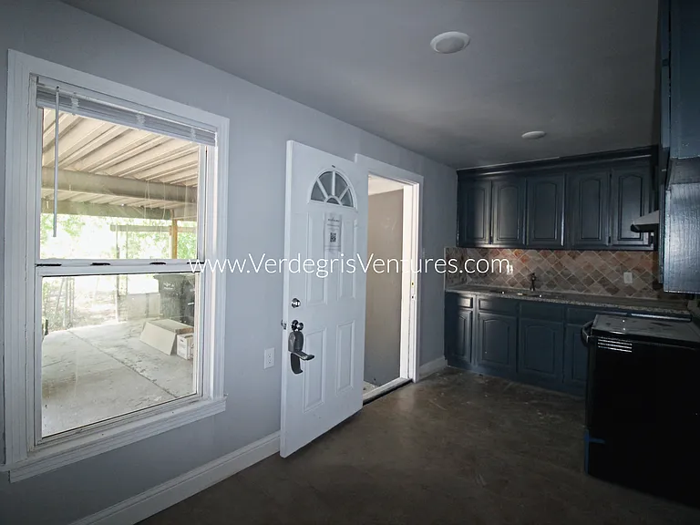 The kitchen is modest in size yet functional, featuring granite counters, stainless steel sink and appliances, a west_facing window for natural light, and direct access to the carport