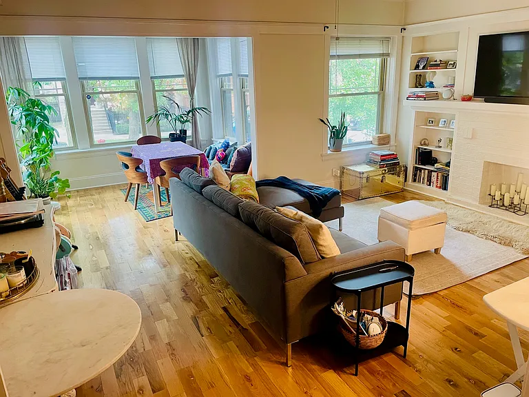 Beautiful living room area with storage shelving built-in. Stunning hardwood throughout apartment