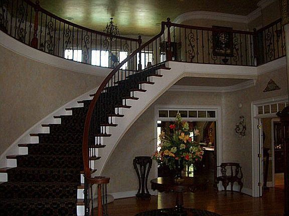 The curving staircase has been reworked with wrought iron railings.