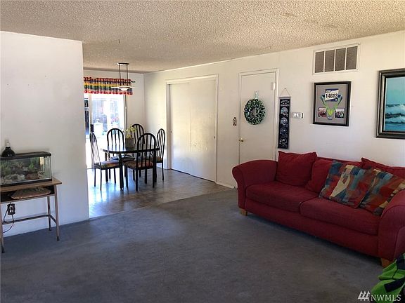 Living room with adjoining dining area. The door next to the couch leads to a bonus and utility room.  