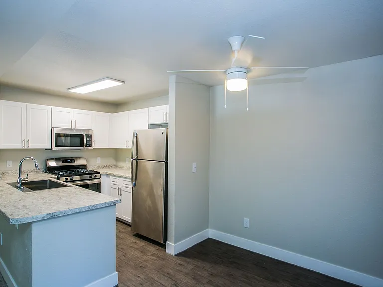 Kitchen and dining area with ceiling fan and wood-style flooring.