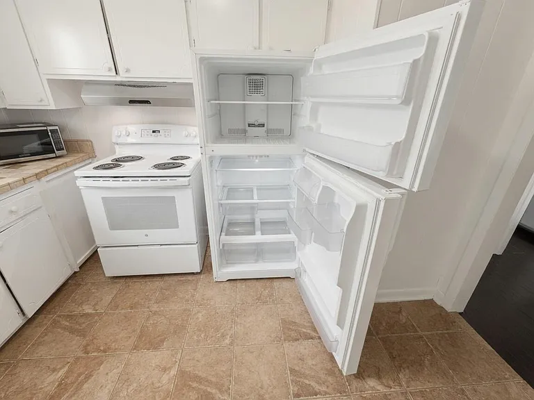 Functional kitchen with ample cabinet storage, laminate counters, and a full appliance set including range and refrigerator.