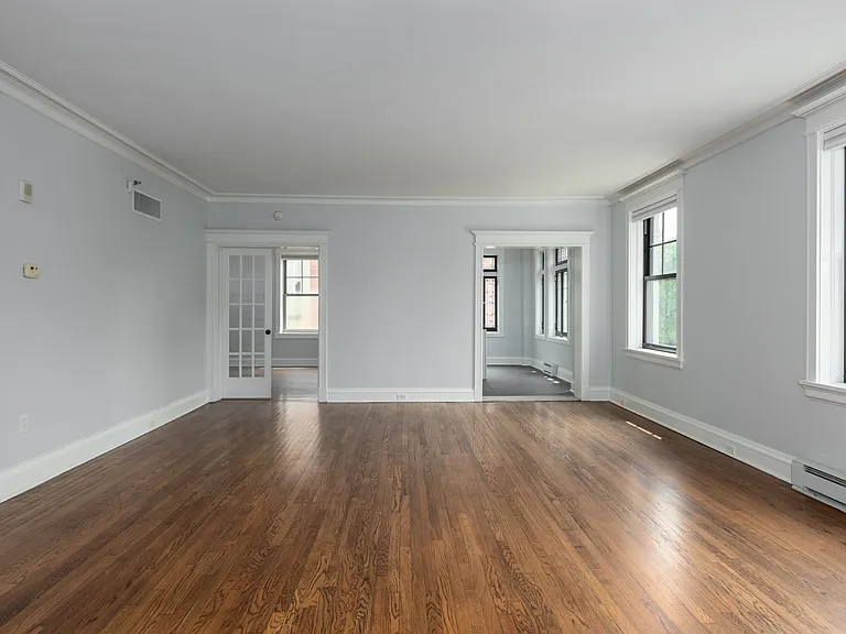 York House large living room with oak hardwood flooring, crown molding and french doors.
